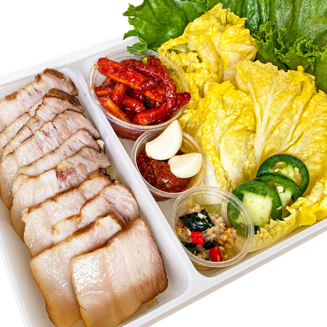 Sliced bossam pork belly with fresh cabbage, lettuce, garlic, and ssamjang